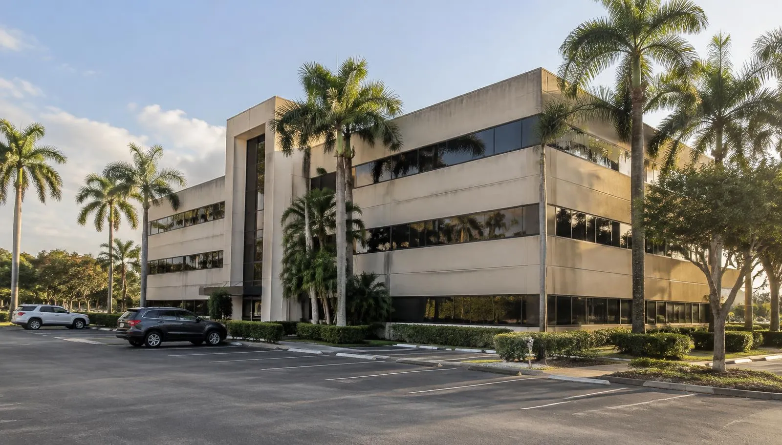 An aging suburban commercial office building in South Florida with a partially empty parking lot and fading facade.