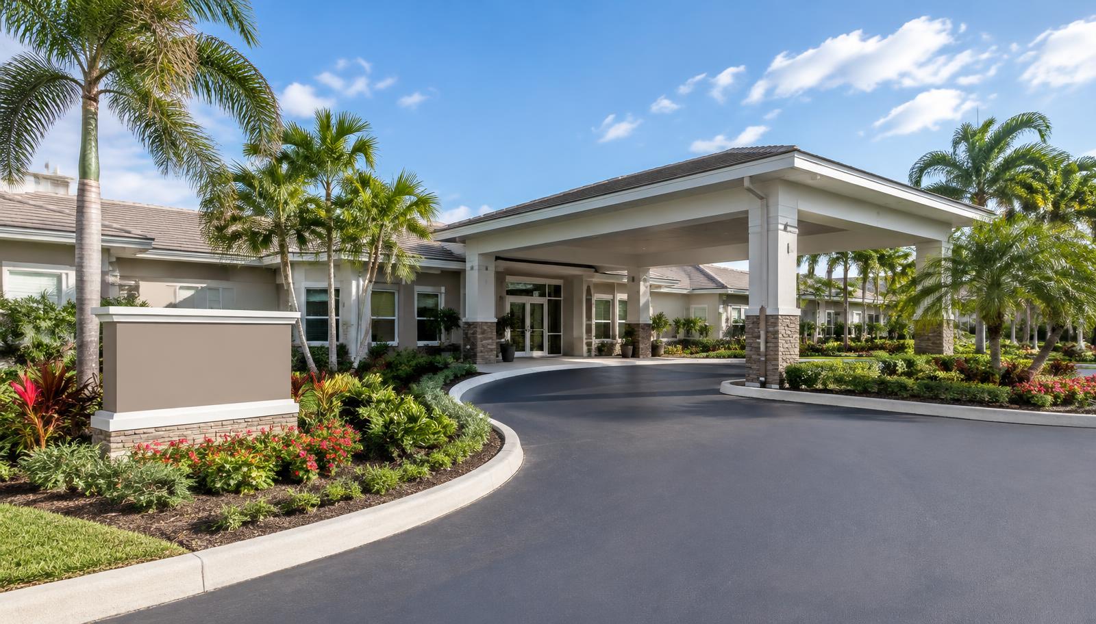 A modern commercial assisted living facility in South Florida featuring a paved driveway, landscaped gardens, and a covered resident drop off area.
